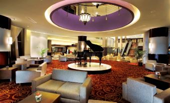 a large room with a grand piano in the center , surrounded by chairs and couches at ASTON Purwokerto Hotel & Convention Center