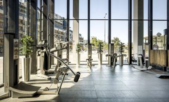a modern gym with large windows , clear blue skies , and various exercise equipment , including a stationary bike at Fletcher Wellness-Hotel Leiden