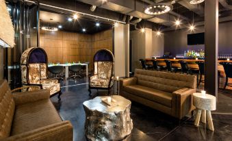 a modern lounge area with a leather couch , wooden coffee table , and a bar in the background at Hotel Nyack, A Joie de Vivre Hotel by Hyatt