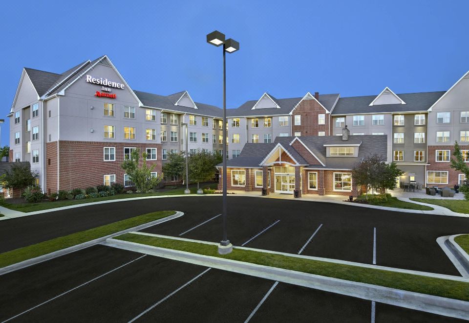 a large hotel building with a parking lot in front of it , surrounded by trees at Residence Inn Waldorf