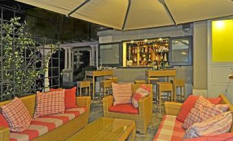 a cozy outdoor area with red and white furniture , wooden tables , and umbrellas , as well as an outdoor bar and lounge area at Hotel Europa