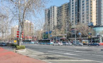 On both sides of a city street, there are cars and buildings, with an empty space along the road at Peony Hotel