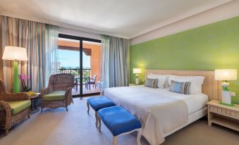 a large bed with a blue headboard is in a room with green walls and a sliding glass door leading to an outdoor balcony at Cascade Wellness Resort