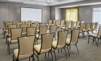 a conference room with rows of chairs arranged in a semicircle , and a projector screen mounted on the wall at SpringHill Suites Long Island Brookhaven
