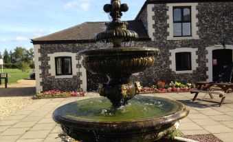 a large stone building with a fountain in front of it , surrounded by lush greenery at Coach House Hotel