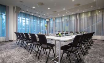 a conference room with a white table surrounded by black chairs and large windows , creating a bright and spacious atmosphere at Radisson Blu Airport Hotel, Oslo Gardermoen