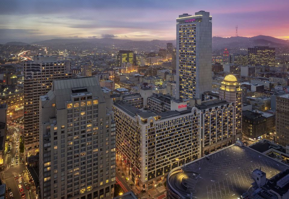 a cityscape at dusk , with a large building in the foreground and several other buildings in the background at Hilton San Francisco Union Square