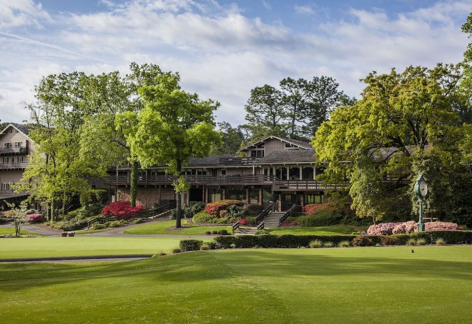 a large wooden building surrounded by a lush green golf course , with trees in the background at Pine Needles Lodge & Golf Club