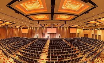 a large , well - lit conference room with rows of chairs and a stage at the front at Pullman Melbourne Albert Park