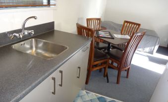 a small kitchen with a sink , dining table , chairs , and a window with blinds at Argyle on the Park