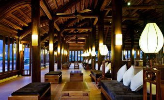 a long hallway with wooden floors and walls , a ceiling fan , and multiple beds on both sides at Emeralda Resort Ninh Binh