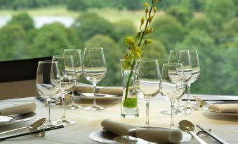 A table is set for two with wine glasses and napkins in the middle of an outdoor setting at Royal Garden Hotel