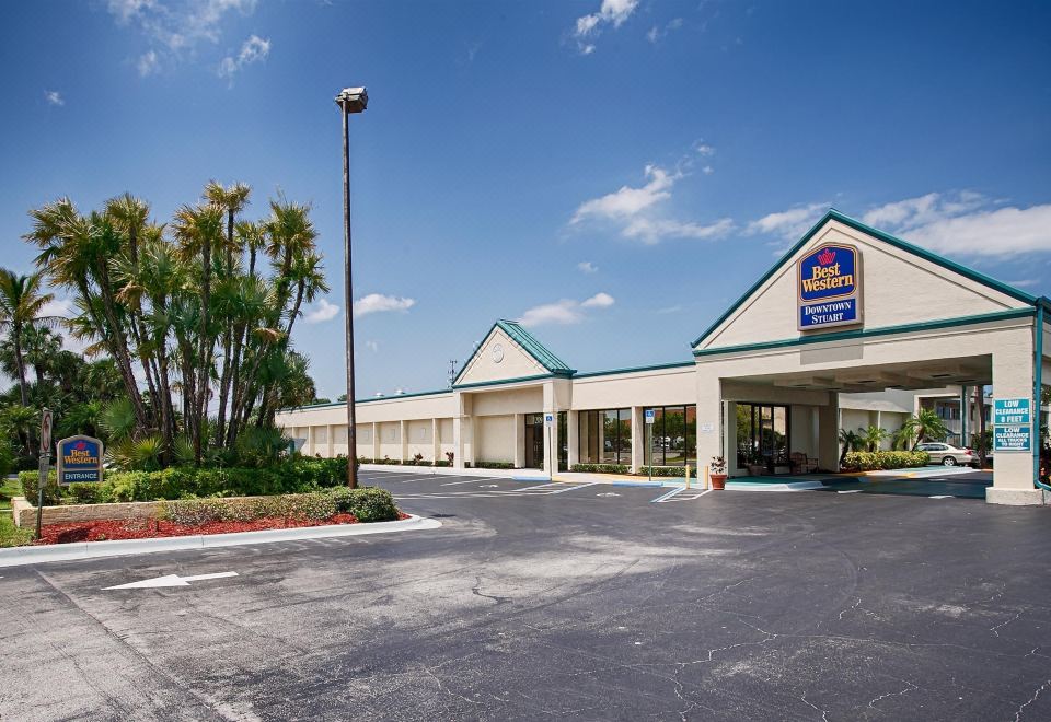 "a long , beige - colored building with a blue roof and the word "" best western "" on it , surrounded by trees and a parking lot" at Best Western Downtown Stuart