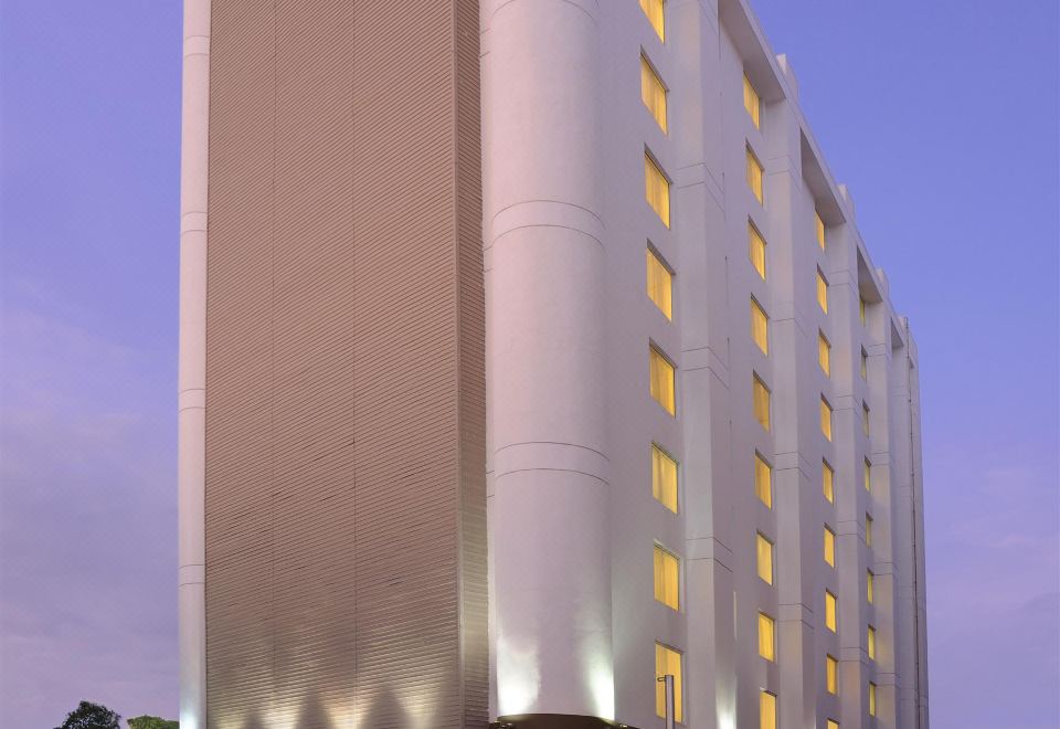 a tall building with a white facade and many windows is illuminated by the light at Four Points by Sheraton Ahmedabad