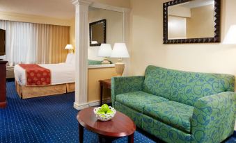a hotel room with a couch , coffee table , and bed , along with the walls decorated in white at SpringHill Suites Centreville Chantilly