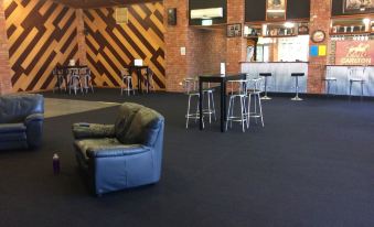 a large room with a blue couch and chairs , wooden walls , and tables in the background at Kerang Motel