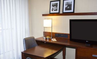 a hotel room with a desk , lamp , and chair , along with framed pictures on the wall at Courtyard by Marriott Los Angeles Pasadena/Monrovia