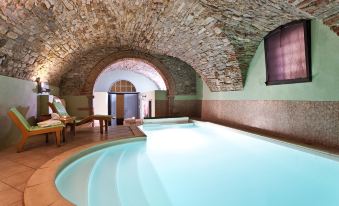 an indoor swimming pool surrounded by a stone wall , with a bench placed near the pool at Palazzo Leopoldo Dimora Storica & Spa