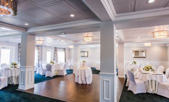 a large , white dining room with multiple tables and chairs set up for a wedding reception at Danfords Hotel & Marina