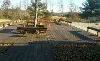 a wooden deck with several chairs and a tree in the background , surrounded by grass and trees at Athens Lodge