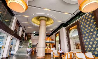 a large , modern hotel lobby with high ceilings , multiple potted plants , and comfortable seating arrangements at Viva Hotel Songkhla