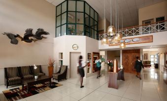 a group of people are standing in a large lobby with a glass ceiling and walls at Maun Lodge