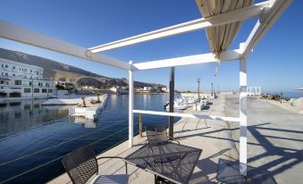 a patio with a table and chairs overlooks the water , with boats in the distance at Hotel Tirreno