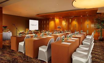 a conference room set up for a meeting , with tables and chairs arranged in rows at Oakwood Premier Cozmo Jakarta