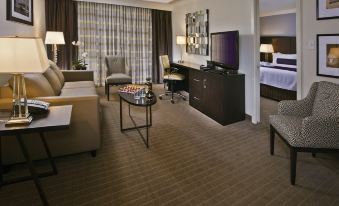 a well - furnished hotel room with a living area , dining table , and two beds , all set against a backdrop of a window with curtains at Crowne Plaza Suffern-Mahwah, an IHG Hotel