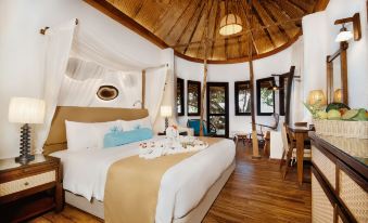 a luxurious bedroom with a round bed in the center , surrounded by wooden furniture and decorations at Makunudu Island