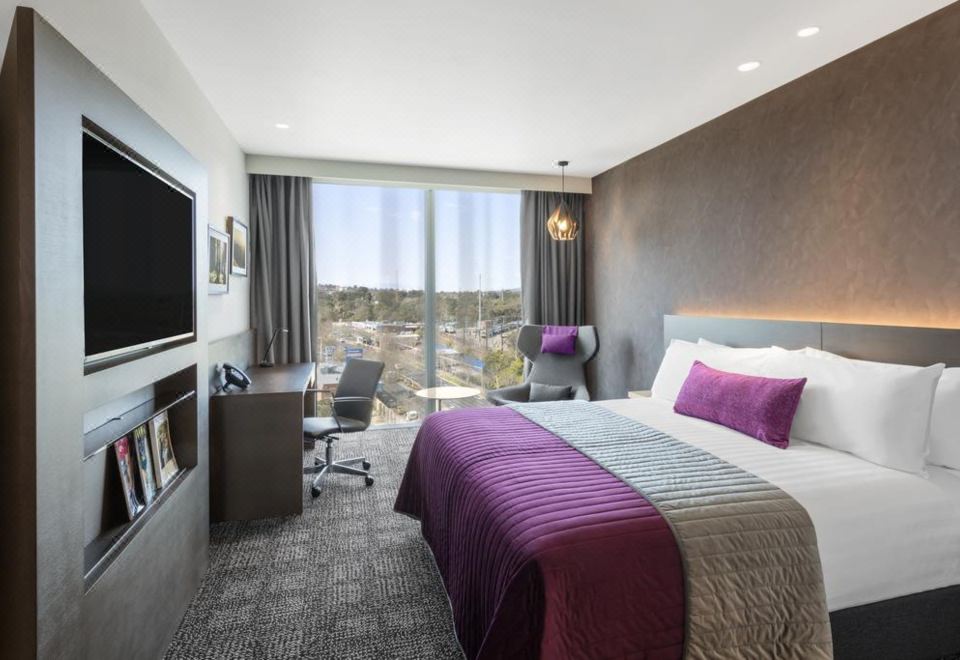 a modern hotel room with a large window , a bed , a desk , and a tv at Sage Melbourne Ringwood