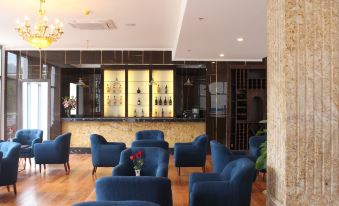 a well - lit hotel lobby with blue chairs and couches , as well as a bar area at Phoenix Hotel