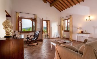 a spacious living room with wooden floors , large windows offering views of the countryside , and comfortable seating arrangements at Abbadia Sicille Relais