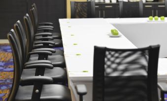a conference table with white tablecloth and black chairs , set for a meeting or presentation at Courtyard Toluca Tollocan
