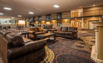 a spacious , well - lit living room with brown leather couches and chairs arranged around a coffee table at Best Western Wichita North