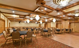 a large , well - lit dining room with multiple round tables and chairs arranged for a formal event at Best Western Prairie Inn  Conference Center