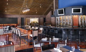 a restaurant with wooden tables and chairs , a bar area , and a television mounted on the wall at Delta Hotels by Marriott Baltimore Hunt Valley
