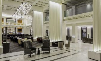 a large , well - lit room with white columns and a black marble floor is furnished with black chairs and tables at Hilton Boston Park Plaza