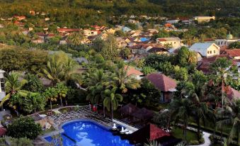 an aerial view of a resort with a large pool surrounded by palm trees , mountains in the background at Sahid Bela Ternate