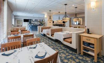 a restaurant with multiple dining tables and chairs , some of which are covered with white tablecloths at Holiday Inn South Kingstown (Newport Area)