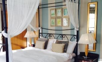 a cozy bedroom with a four - poster bed draped in white sheets and curtains , creating a comfortable atmosphere at Manor Hotel