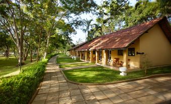 a row of yellow buildings surrounded by green grass and trees , located in a park - like setting at Habarana Village by Cinnamon