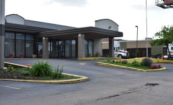 a large , gray building with a parking lot and a truck parked in front of it at FairBridge Inn Express Melrose Park
