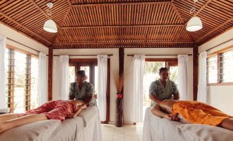 two people are giving each other a massage in a room with wooden walls and ceiling at Sinalei Reef Resort & Spa