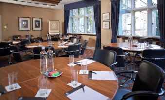 a conference room with round tables and chairs , water bottles , and papers on each table at The Abbey