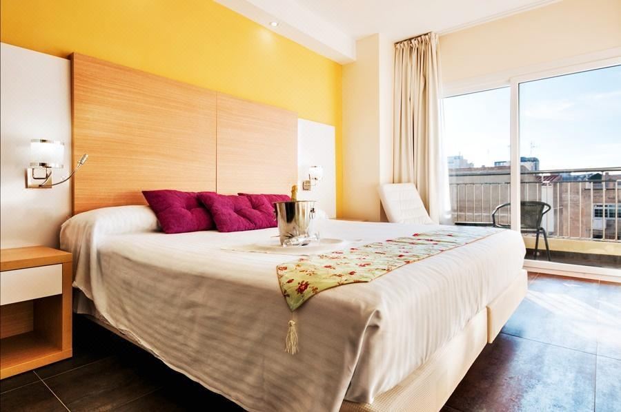 a large bed with white sheets and pink pillows is in a room with yellow walls at Hotel Fontana Plaza