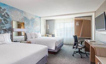 a hotel room with two beds , a desk , and a chair , all neatly arranged in the space at Courtyard Dallas Flower Mound