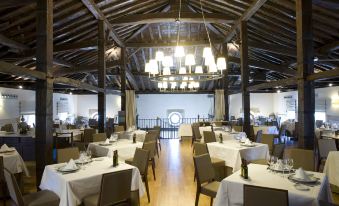 a large dining room with wooden tables and chairs , white tablecloths , and a chandelier hanging from the ceiling at Parador de Argomaniz