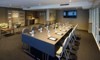 a conference room with a long table and multiple chairs arranged for a meeting , along with a tv mounted on the wall at Pacific Hotel Cairns