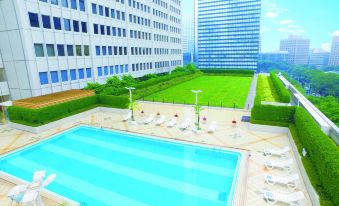 There is a rooftop swimming pool with chairs and tables located in an urban area surrounded by tall buildings at Keio Plaza Hotel Tokyo